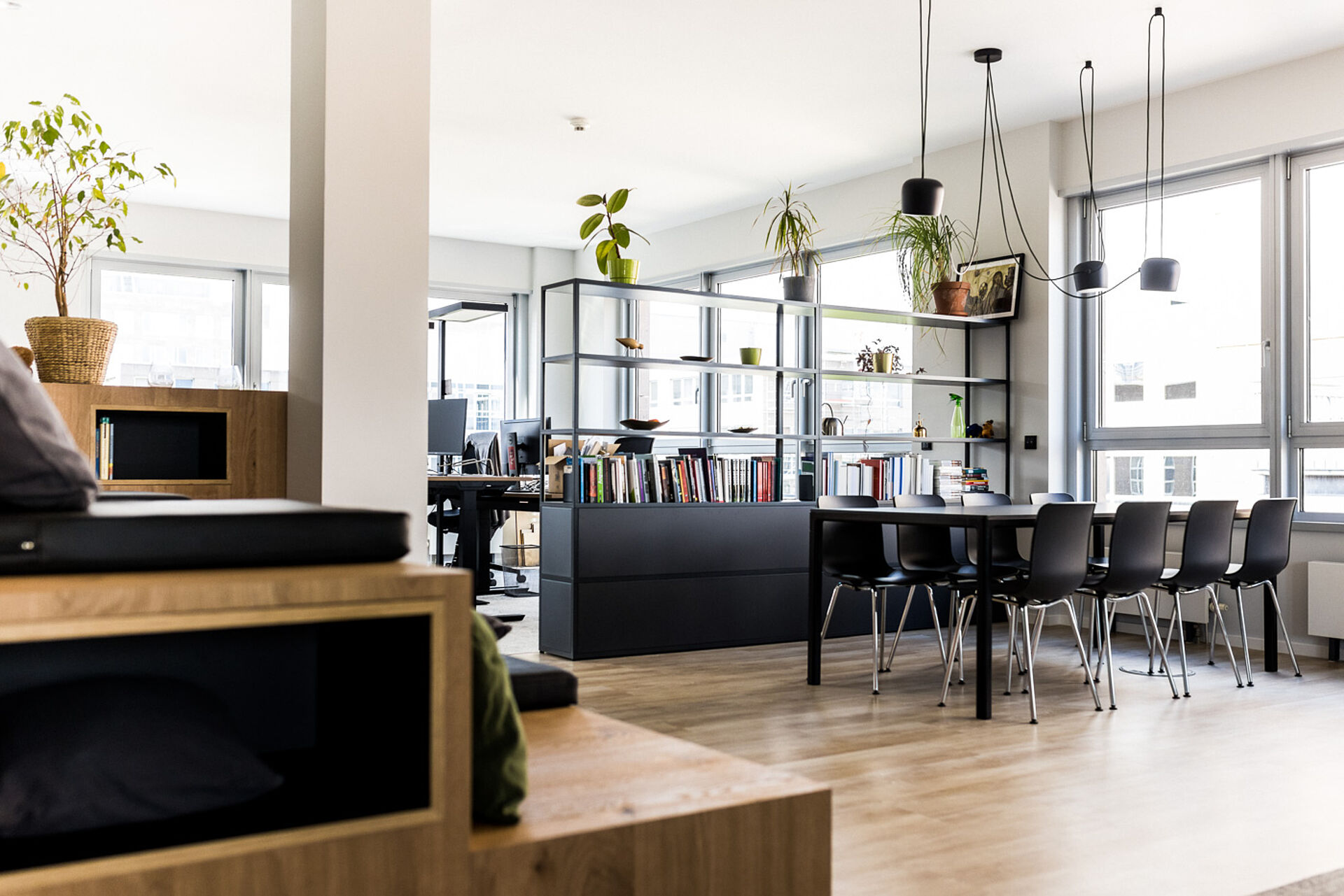 Bright meeting room with a long table, several chairs, bookshelves and large windows in a modern office setting.